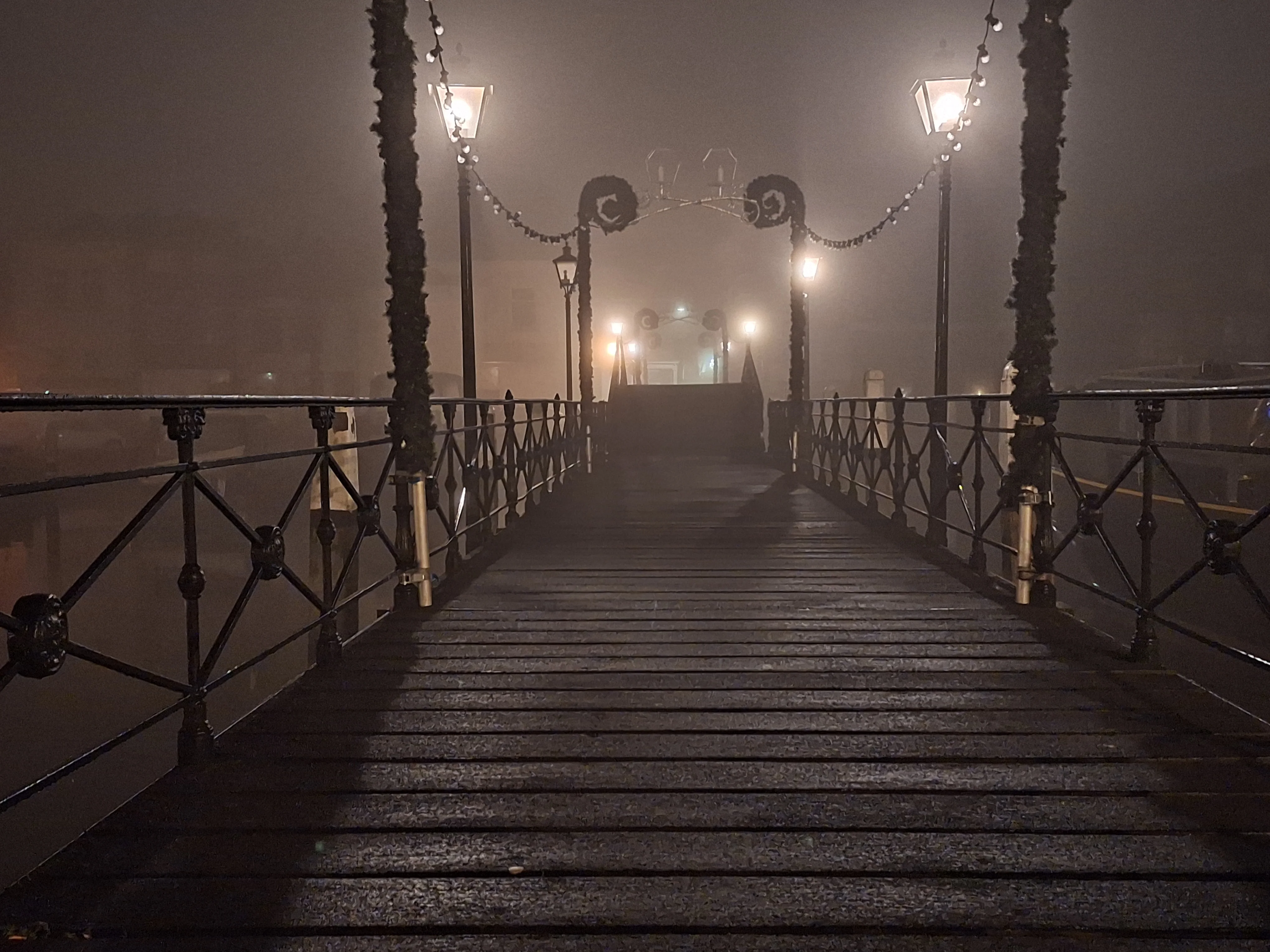 Illuminated bridge disappearing into dense fog